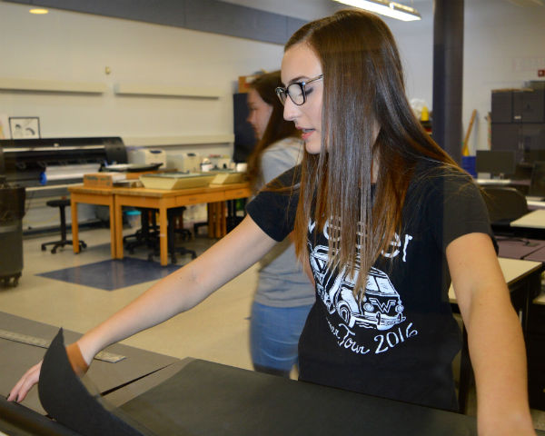 Sophomore Gia Caruso of Howell cuts black paper to cover the cafeteria locker pods and set up for Photo Club’s photobooth.