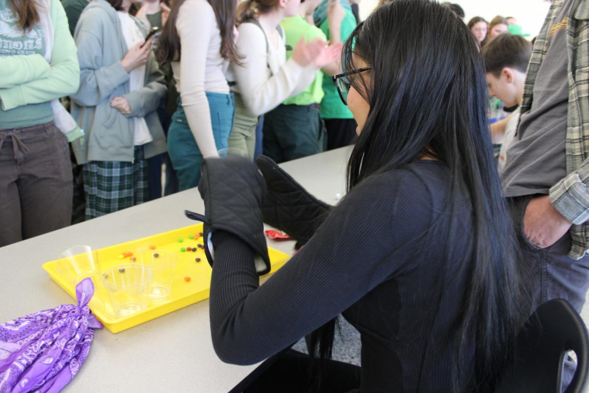 Senior Chloe Nyugen attempts to sort skittles with a pair of oven mits.