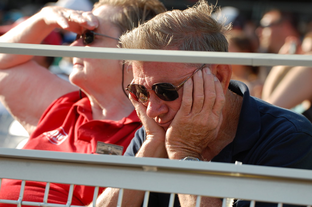 A fan watches a team play from the bleachers, disappointed in their performance. “A tired and/or sad fan in the front row” by Minda Haas Kuhlmann is licensed under CC BY 2.0.